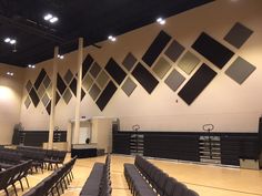 an empty gymnasium with rows of chairs and black dividers in front of the wall