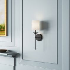 a wall light mounted on the side of a white door with a painting in the background