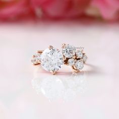 an engagement ring with three diamonds on it and a pink rose in the foreground