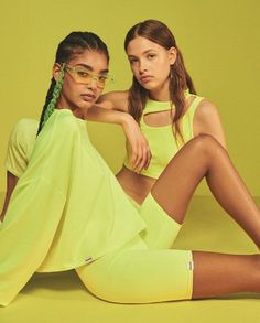 two young women sitting on the ground in yellow outfits