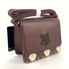 the hogwarts crest on this brown leather purse is embellished with harry potter symbols