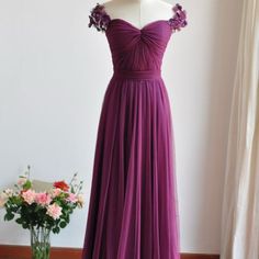 a purple dress is on display in front of a vase with flowers and a flower pot