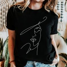 🖤FIND MORE TREASURES at MetisArtPrints * Explore our t-shirt collection! https://etsy.me/4bJMLv4 * Explore unique artworks! https://etsy.me/2Rw7KcO 🖤ABOUT Embrace minimalist style with the Woman Face Line Art T-shirt. This contemporary T-shirt features a mesmerizing abstract one-line drawing of a woman's face. It is perfect for those who appreciate simple yet expressive design. Its clean lines and aesthetic appeal make it versatile for any occasion. It is the ideal addition to any wardrobe for Artistic Crew Neck Top, Artistic Black Tops With Relaxed Fit, Artistic Black Tops For Spring, Artistic Black Top With Relaxed Fit, Artsy Black Top With Screen Print, Black Artsy Tops With Graphic Design, Artsy Black Tops With Graphic Design, Trendy Crew Neck Tops For Artistic Expression, Single Line Art Simple