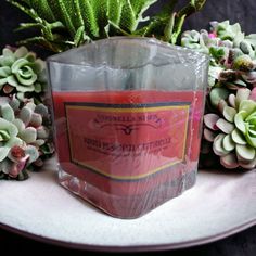 a pink candle sitting on top of a white plate next to succulents