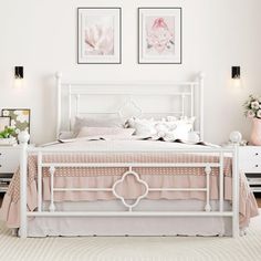 a white bed sitting in a bedroom next to two pictures on the wall above it