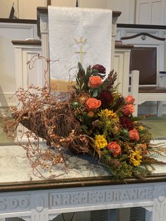 an arrangement of flowers and branches on a table in front of a church altar with a cross