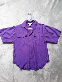 "100% washable silk camp shirt from Casual Corner. Color is more intense and to the red side of purple than photos show. Pic showing care tag is truer to color. Wear alone or layer with tank top. Buttons down center and on front pockets, short sleeves. Great condition; no tears or holes. Couple fade spots underarm seam. Tag states Medium, however it runs small. Measurements are taken flat and double where appropriate: Bust 40\" (taken from underarm seam, across shirt, to opposite seam) Arm openi Dark Purple Shirt, Purple Clothing, Purple Relaxed Fit Short Sleeve Shirt, 90s Style Purple Short Sleeve T-shirt, Purple Relaxed Fit Shirt With Buttons, Summer Purple Button-up Shirt, Purple Oversized Short Sleeve Top, Royal Purple Color, Purple Shirt