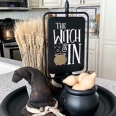 a witch's hat, caulder and broom sit on a black plate