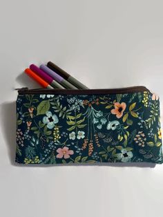 "This listing has six options to choose from. All pouches are made with a high quality Rifle Paper fabric print on the outside.  Interfaced for stability. Secured with a quality zipper. The inside is lined with 💯 cotton fabric. Dimensions: 9\" in length x 5\" in length. Perfect as a pencil case, cosmetics case, cash holder or accessory pouch.  Care: wash in a gentle cycle using cold water and air dry for best results.  Thank you for visiting Gratitude Oasis." Portable Pencil Organizer As Gift, Rectangular Pencil Case With Card Slots For School, Pencil Cosmetic Bag With Pen Holders For Everyday Use, Everyday Use Pencil-shaped Cosmetic Bag With Pen Holders, Green Pencil Case Pouch With Pen Holders, Rectangular Zipper Pouch Stationery, Multicolor Stationery Pouch With Pen Holders, Multicolor Pouch Pen Holder, Multicolor Stationery With Pen Slots For Storage