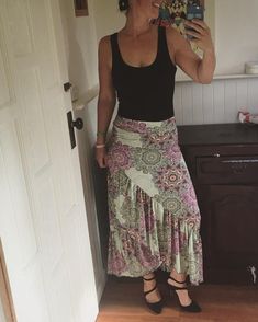 a woman is taking a selfie in the mirror while wearing a skirt and black tank top