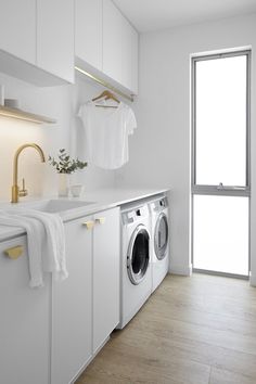 a washer and dryer in a white laundry room next to a large window