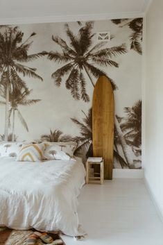 a bedroom with palm trees on the wall and a surfboard leaning against the wall