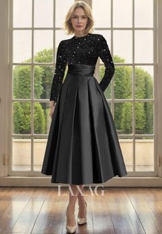 a woman standing in front of a window wearing a black dress with sequins on it