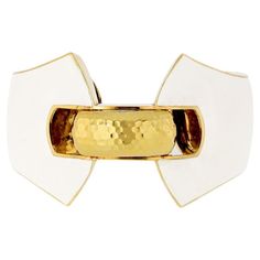 a gold and white cuff with two pieces of metal on it's sides, one piece