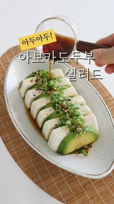 a person holding chopsticks over a plate with food on it and an advertisement in the background