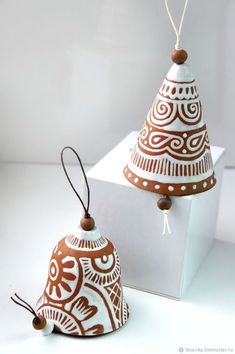 two brown and white ornaments hanging from strings on top of each other in front of a white box