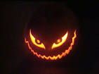 a carved pumpkin with an evil face on it's side, lit up in the dark