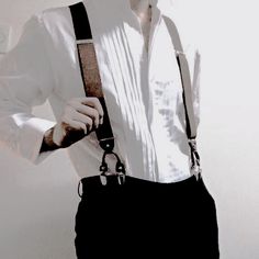 a man wearing suspenders and a white shirt is holding his hands on his hips