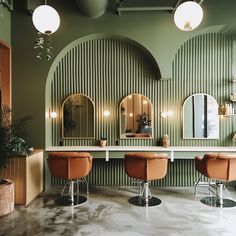 a salon with stools and mirrors on the wall, lights hanging from the ceiling