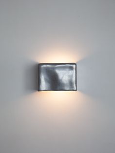 a wall light that is on the side of a white wall with a black leather case