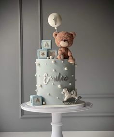 a teddy bear is sitting on top of a baby's first birthday cake,