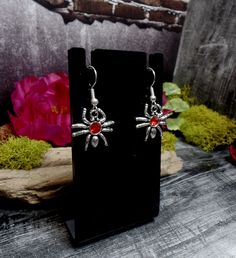 "These earrings features cool tiny spider charms with red rhinestones in them. They are on silver plated ear wires. Small but so cute! Earrings are 1 1/2\" total length and 3/4\" wide *Color may vary slightly due to camera flash or individual computer monitors Store policies: https://www.etsy.com/shop/eternalnightboutique#policies Back to the shop: https://www.etsy.com/shop/eternalnightboutique" Themed Red Earrings, Red Novelty Jewelry For Halloween, Red Pierced Halloween Earrings, Red Pierced Earrings For Halloween, Silver Themed Earrings For Halloween, Red Novelty Drop Earrings, Halloween Themed Silver Earrings, Nickel-free Red Halloween Jewelry, Red Nickel-free Jewelry For Halloween