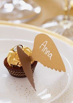 a white plate topped with a chocolate cupcake covered in gold foil and an angel cutout