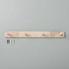 a wooden coat rack with three pegs attached to it and two screws on each side