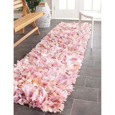 a large pile of pink tissue paper sitting on top of a floor next to a wooden bench