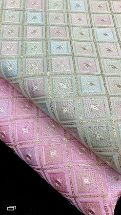 two pink and light blue fabrics on top of each other, one with gold thread