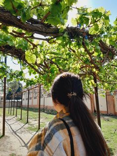 a woman with long hair standing under a tree