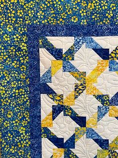 a blue and yellow quilted wall hanging