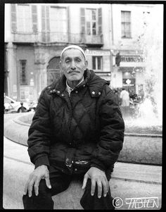 an old man sitting on the edge of a fountain