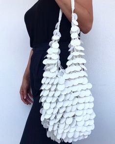 a woman is holding a white bag made out of buttons