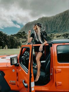 a woman sitting on top of an orange jeep