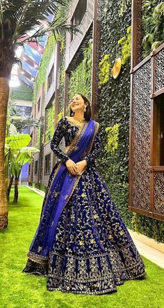 a woman in a blue and gold lehenga standing next to a palm tree