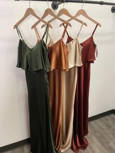 three dresses hanging on a rack in front of a wall