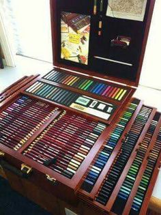 a wooden box filled with lots of different colored pencils on top of a table