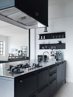 a kitchen with stainless steel counter tops and black cabinets, along with open shelving