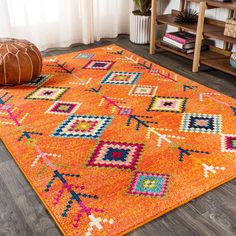 an orange area rug with colorful designs on the floor in front of a wooden shelf