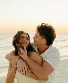 a man and woman hugging on the beach