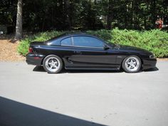 a black sports car parked in front of some bushes