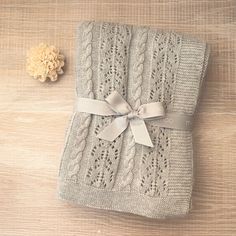 a knitted blanket with a bow tied around it on top of a wooden table