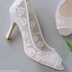 a pair of white high heel shoes next to a plant