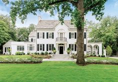 a large white house surrounded by trees and grass