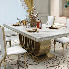 a dining room table with white chairs and gold trimmings on the top, in front of a large window