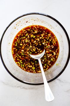 a glass bowl filled with food and a spoon on top of the bowl next to it