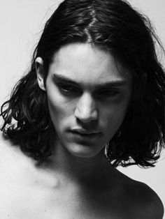 a shirtless man with long hair and no shirt is looking at the camera while he stands in front of a white background