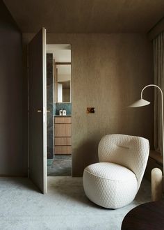 a living room with a white chair and a lamp on the table in front of it