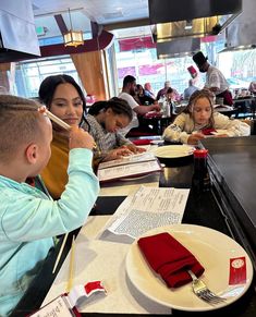 a group of children sitting at a table in a restaurant with menus on it